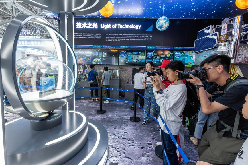 Visitors take photos of lunar samples collected by the Chang'e-6 mission from the moon's far side, on display at the 15th China International Aviation and Aerospace Exhibition in Zhuhai, south China's Guangdong province, Nov. 16, 2024. (Pho'to/Ding Yi)