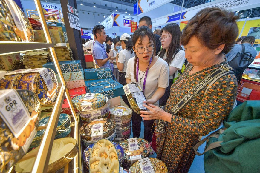 A woman buys Malaysian products at the 22nd China-ASEAN Expo (CAEXPO), Sept. 20, 2025. (Photo/Peng Huan)