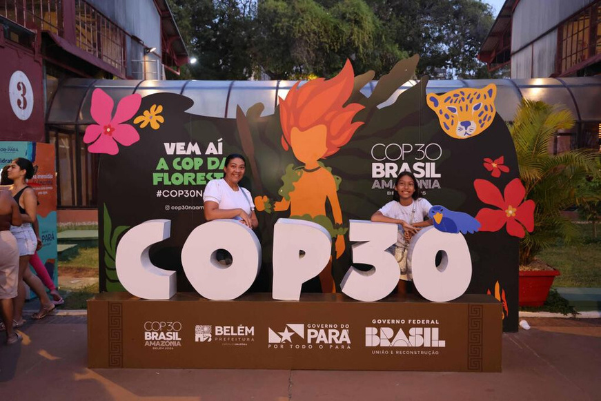 Tourists post for a picture with a COP30-themed installation in Belem, Brazil. (People's Daily/Shi Yuanhao)