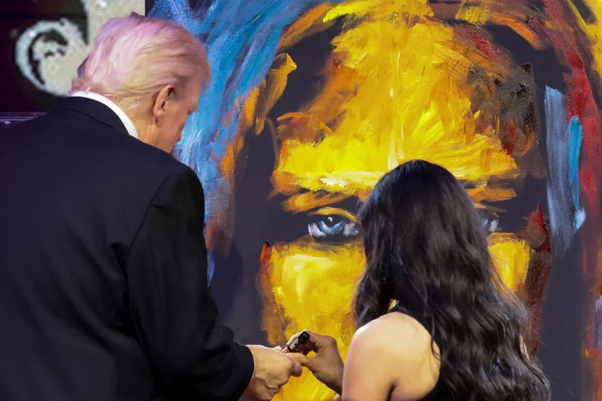 Le président Trump signe un tableau de l'artiste Vanessa Horabuena lors d'une fête du Nouvel An dans son club de Mar-a-Lago. Photo : Reuters