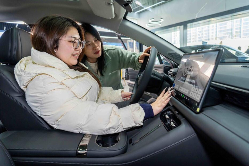 A woman tries out a new energy vehicle at a dealership in Zhangjiagang, east China's Jiangsu province. (Photo/Xing Bin)