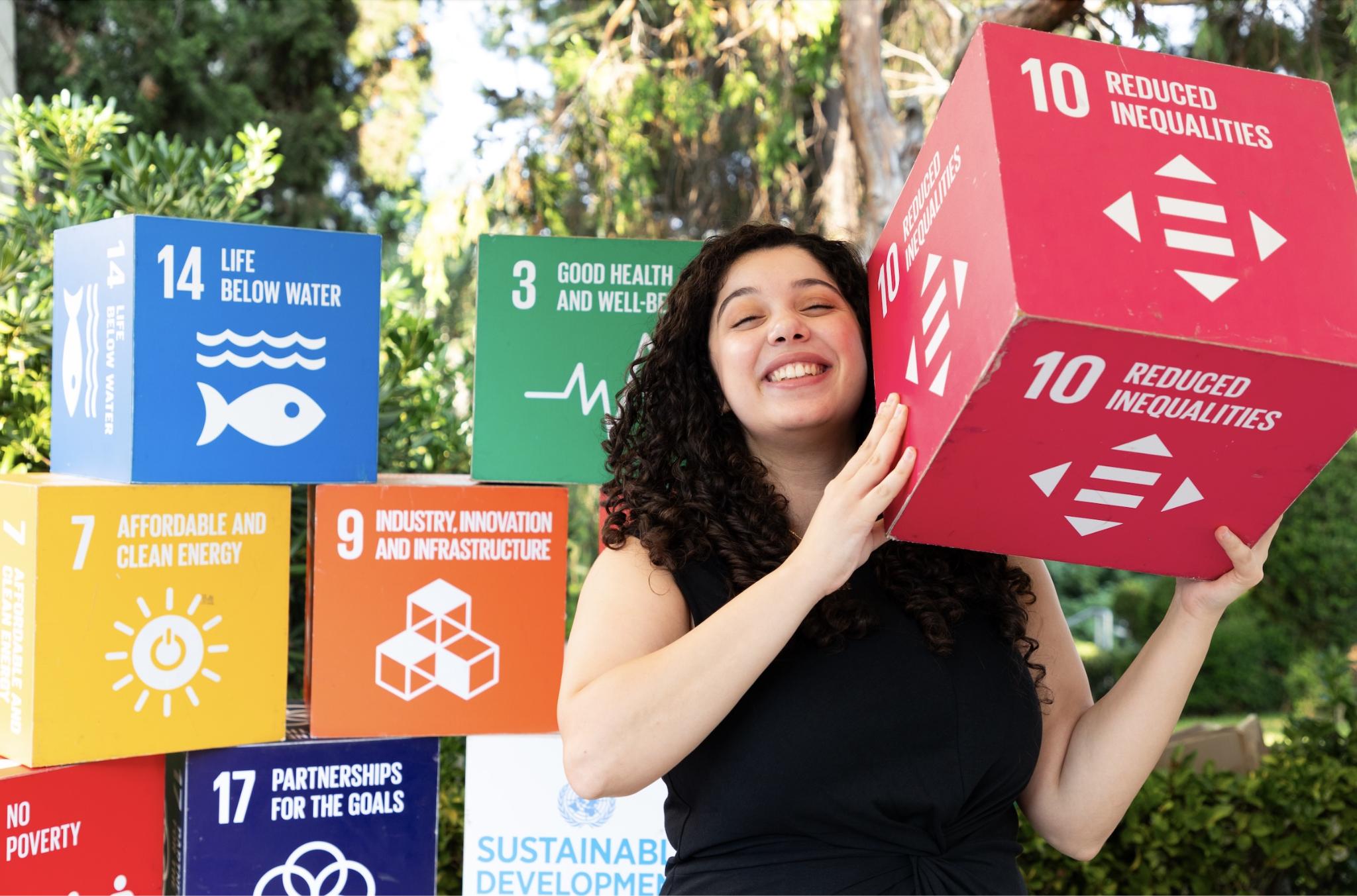 Une jeune femme célèbre la Journée internationale de la Jeunesse en montrant une boîte portant l'ODD 10, « Réduction des inégalités ». Photo : PNUD Liban