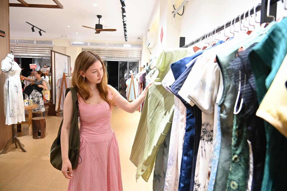 Photo shows a foreign traveler in a shop selling qipao, or mandarin gown, in Ciqikou ancient town in southwest China's Chongqing municipality. (Photo/Sun Kaifang)