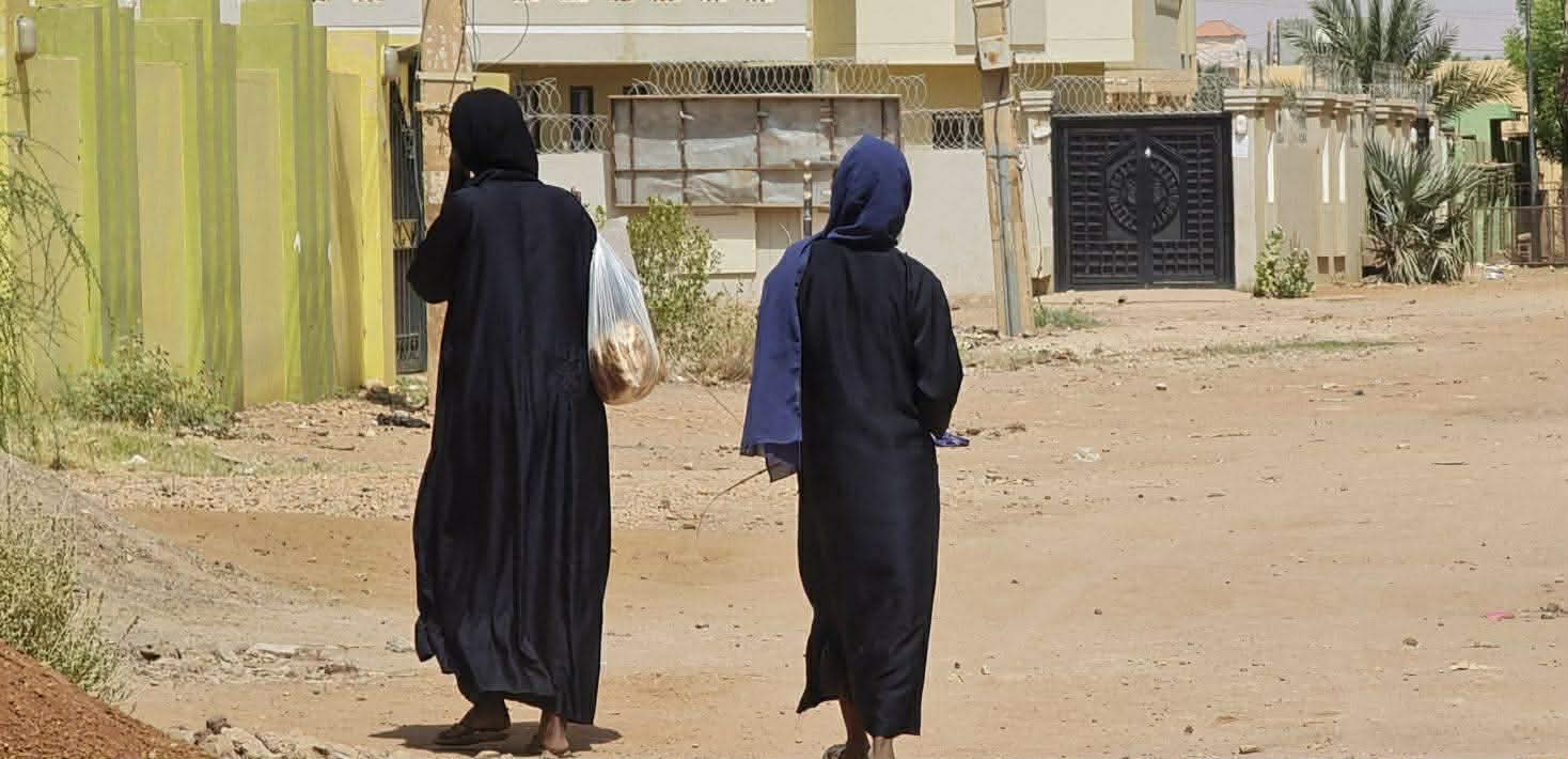 Des femmes, sacs de courses à la main, marchent dans une rue déserte du quartier Jabra à Khartoum. Photo AFP via Getty Images.