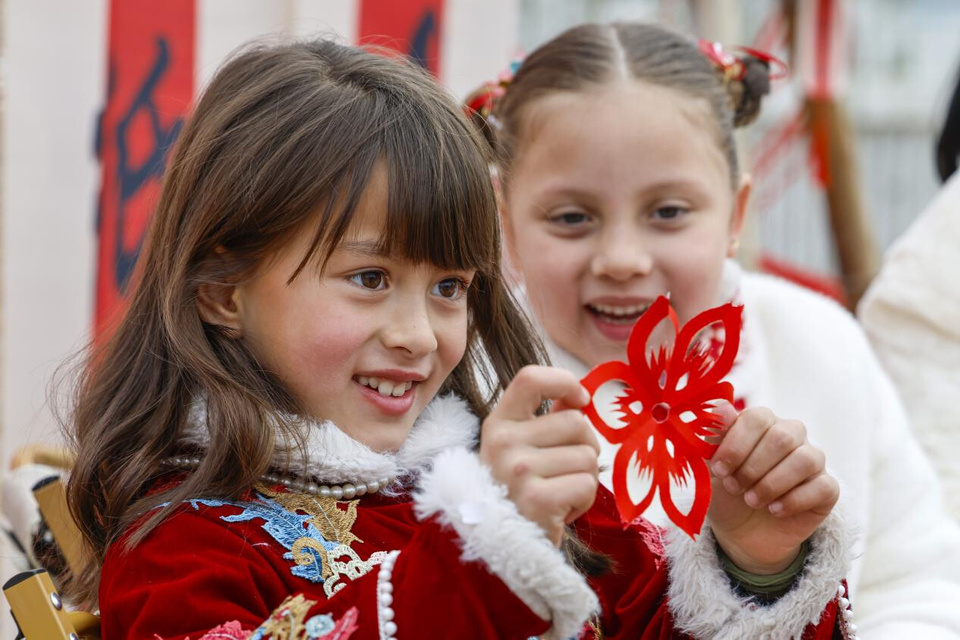 Foreign children experience paper cutting, an intangible cultural heritage item, in Nanxinan village, Huangshan, east China's Anhui province. (Photo/Shi Yalei)