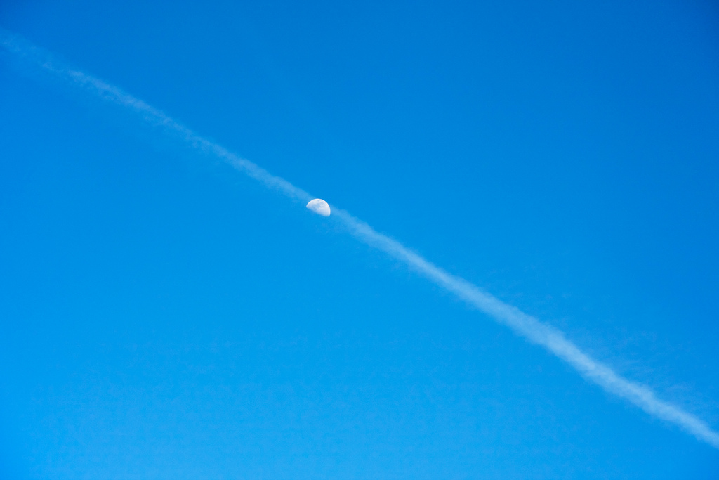 Plane trail crossing the sky over the moon Plane trail crossing the sky over the moon