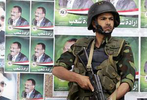 Un soldat yéménite monte la garde devant des affiches du président Ali Abdallah Saleh lors d'un rassemblement (Photo : Reuters)