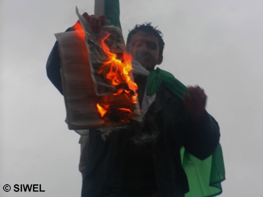 Un étudiant mettant le feu aux deux journaux antikabyles, devant une foule nombreuse ( Photo : Siwel)