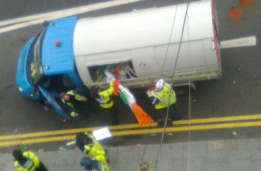 Les Gardai jetant le drapeau national irlandais dans un camion poubelle. Crédit Photo : DR