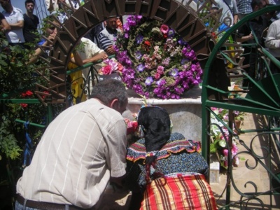 Nna Wiza, mère de Ferhat Mehenni, déposant une gerbe de fleurs sur la tombe de son petit-fils Ameziane assassiné par les forces occultes.(PH/DR)