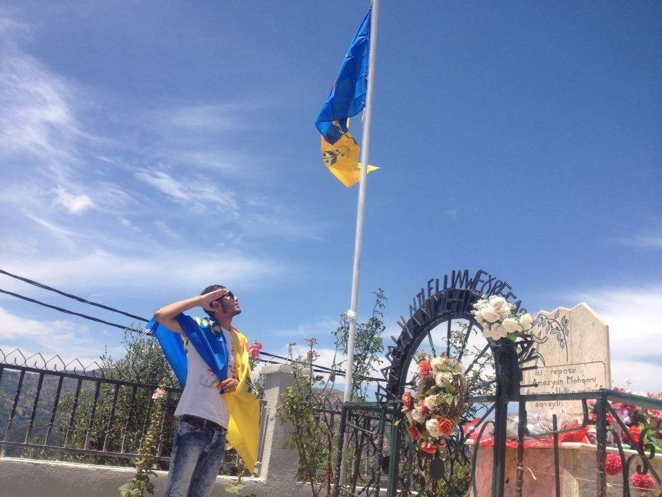 Un jeune kabyle saluant le drapeau kabyle levé à Maraghna en hommage à Ameziane Mehenni (PH/DR)