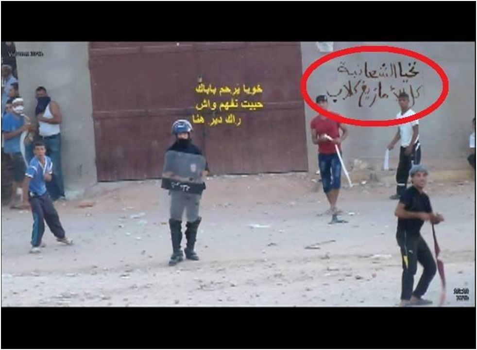 Ici on voit un policier algérien en compagnie de jeunes arabes Châmbas mener une attaque contre les Mozabites. derrière eux, une inscription en arabe est écrite sur le mur disant " Vive les Chaâmbas , tous les amazighs sont des chiens"...mais ce sont les Mozabites qui sont arrêtés manu militari par l'Etat algérien qui démontre sa nature coloniale, profondément raciste et discriminatoire (PH/DR)