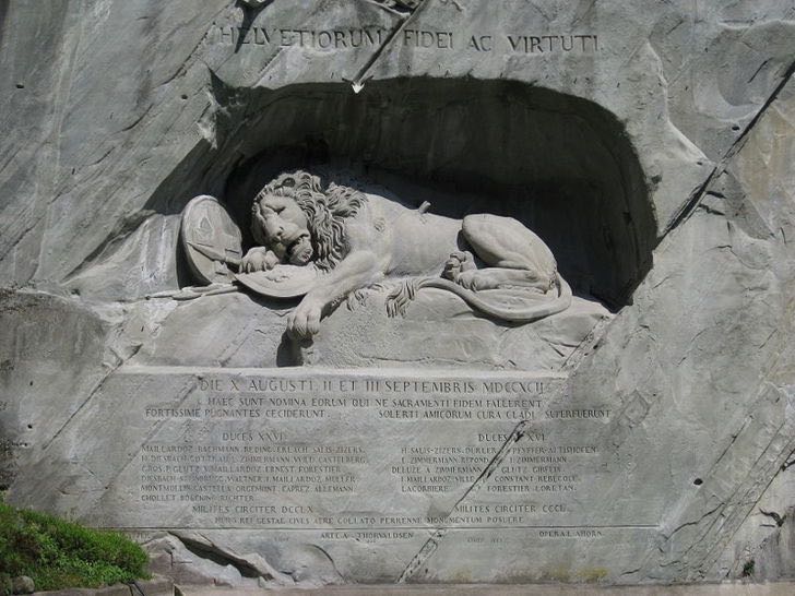 Le Lion de Lucerne mortellement blessé.  Lion mourant avec la mention "à la loyauté et à la bravoure des Suisses", transpercé par une lance couvrant un bouclier portant la fleur de lys de la monarchie française et avec un autre bouclier portant les armoiries de la Suisse.  Dessin du sculpteur danois Bertel Thorvaldsen, taillé par Lukas Ahorn dans une ancienne falaise de grès de Lucerne en Suisse.  Dimension : 10 mètres de long et 6 mètres de haut © Photo : Gürkan Sengün.